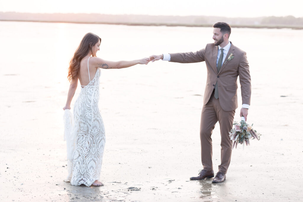 playful bride and groom at the beach