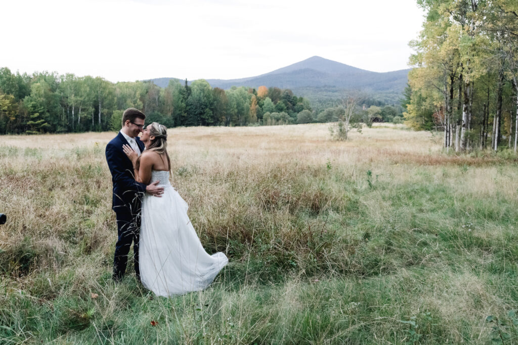 bride and groom in a field with mountain backdrops during their elopement in Maine