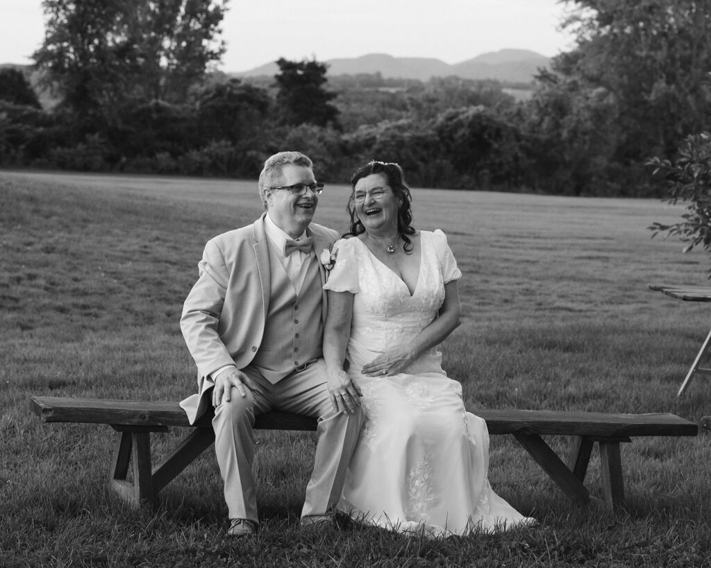 cute older elopement couple sitting on a bench during their maine elopement