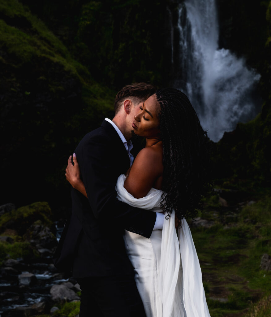 Beautiful mountain waterfall photos are my favorite. The couple is holding each other during their elopement. 