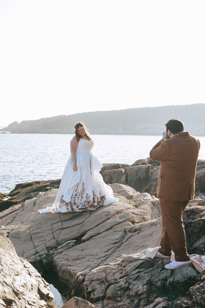 Newlywed couple photographing each other on the rocky coast of Acadia National Park